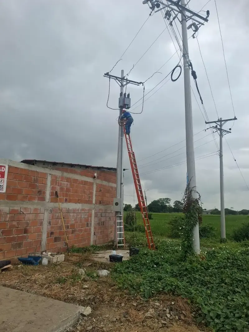 Técnico trabajando en altura sobre una escalera de fibra junto a un poste